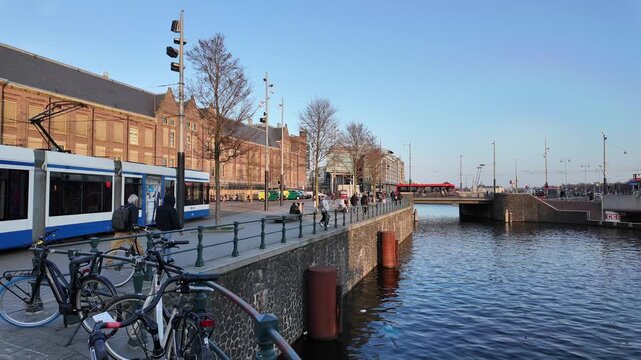 A view of a the shore of a dutch canal in the city centre of Amsterdam with the Kamper bridge visible.