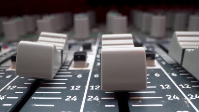 Close up of audio mixer faders and volume control sliders.