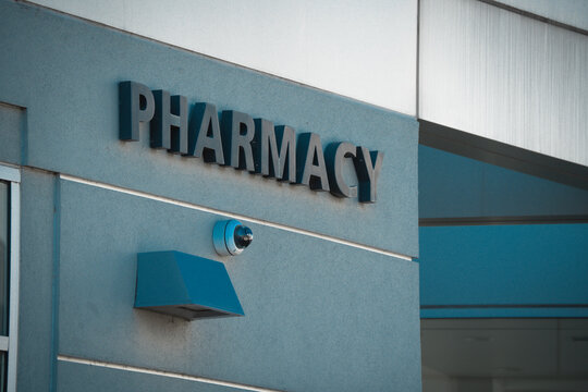Exterior view of a modern pharmacy building with prominent signage and security camera