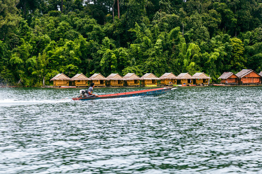 Motorboat passing floating huts on Cheow Lan Lake in Khao Sok National Park