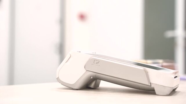 Customer hand holding a modern smartphone to pay at a POS terminal in a clinical setting