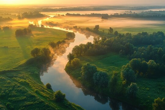 Aerial view of a winding river through misty green fields at sunrise, golden light on trees and calm reflective water conveying peaceful serenity
