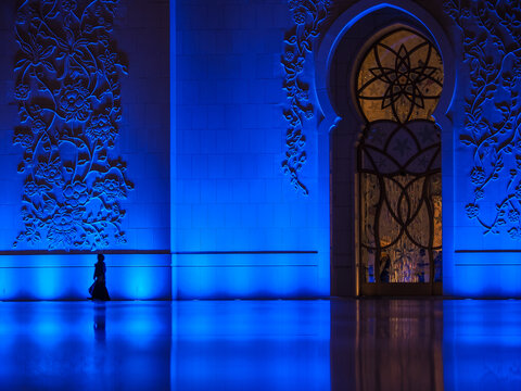 Woman walking by Sheikh Zayed Grand Mosque blue wall copy space