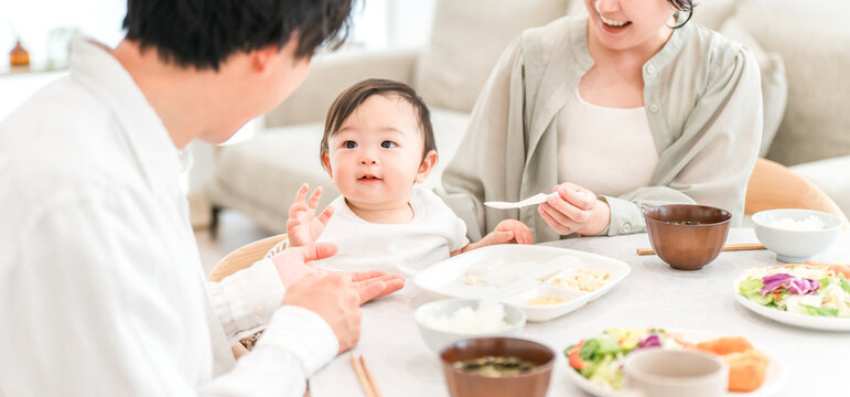 Mothers and fathers feeding their babies solid food and meals at the dinner table (childcare/parenting)