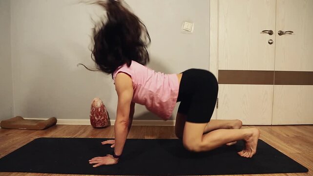 Sport fit strong woman doing active yoga exercise on black mat at home