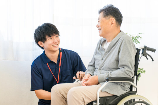 A senior male patient in a wheelchair and a male caregiver/care manager (dementia/rehabilitation).