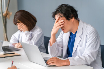 Fototapeta premium A male doctor looking depressed, troubled, and worried while looking at his computer.
