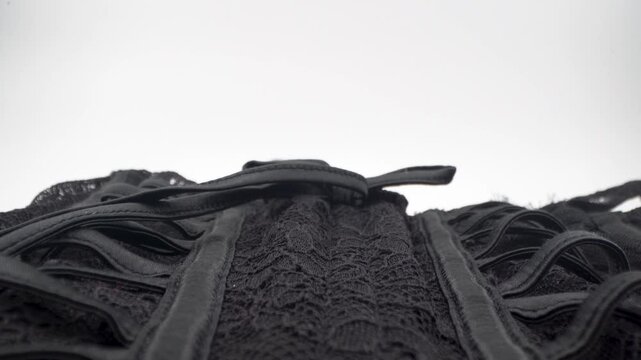 Close up of black corset structure with laces and stitching details.