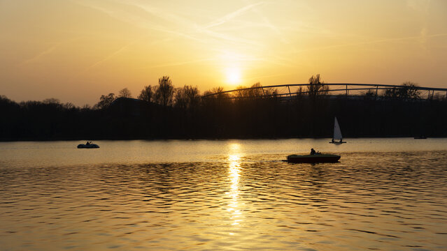 Tranquil evening landscape showing boats and mirrored sunset reflection Maschsee Hanover