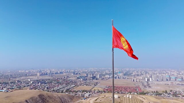 Fluttering Kyrgyzstan Flag View above Bishkek city - aerial view with truck to the left camera movement.