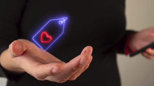 Businesswoman's hand holding an Icon of an animated heart tag in neon light.