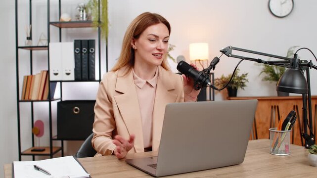 Middle-aged businesswoman at home office runs live with microphone gestures answers questions thanks for donation. Freelancer girl at table reads chat invites to next stream saves notes and posts link