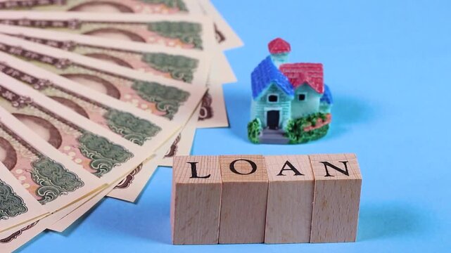 1万円札とミニチュアハウスとLOANの文字ブロック  回転
