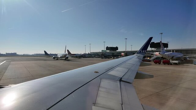 A view of the wing of a Scandinavian Airlines aircraft preparing to depart Amsterdam Airport Schipol on a sunny day.