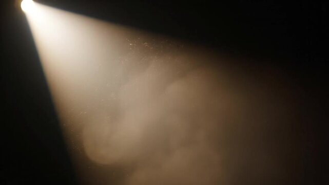 Cinematic warm spotlight shining from the top left corner across a dark black background, illuminating floating dust particles within a distinct diagonal conical light beam.