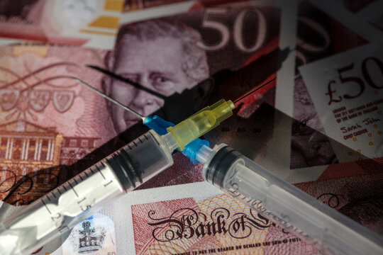 Two plastic syringes against a background of 50 British pound notes