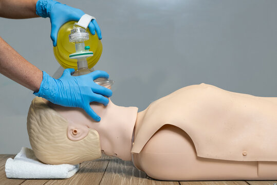 The use of an ambu bag or bag valve mask being demonstrated on a medical dummy 