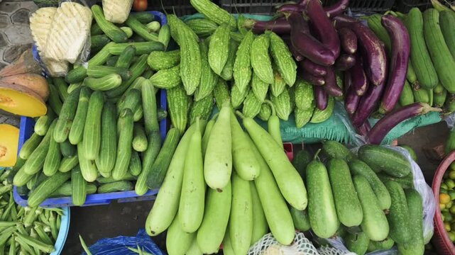 Colorful Vietnamese Street Market Gourd Display Overflowing With Fresh Bottle Gourd, Bittergourd And Purple Eggplant Arranged On Baskets, Close Overhead View Showing Texture, Vendor