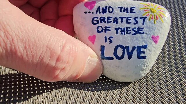 And the greatest of these is love kindness rock moved around with hand