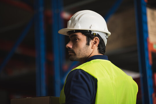 Male worker safety helmet reflective vest warehouse logistics storage inventory shipping distribution industrial environment professional focus and determination