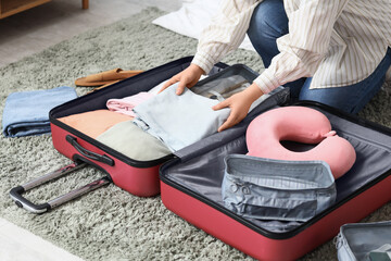 Young woman packing suitcase for travelling in bedroom © Pixel-Shot