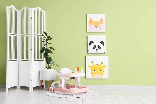 Interior of children's room with baby walker, folding screen and pictures