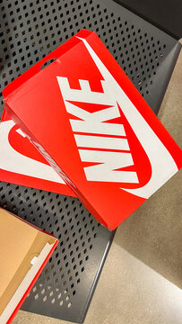 Red Nike shoebox with iconic logo displayed on a textured surface, showcasing branding and packaging design elements