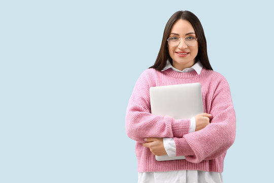 Beautiful young female programmer with laptop on blue background