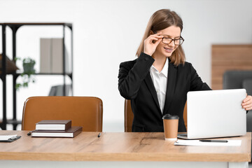 Fototapeta premium Beautiful young businesswoman with laptop at desk in office