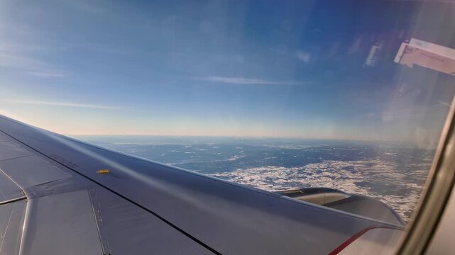A view out the window of a Scandinavian Airlines aircraft flying low over a winter landscape on approach to Oslo Airport Gardermoen.