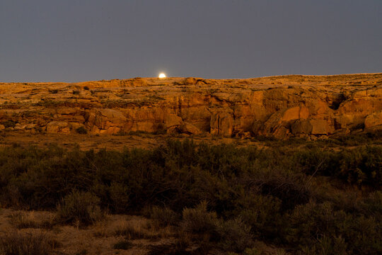 USA, New Mexico, Chaco Canyon.  The moon rising over cliff on the east rim of the canyon.