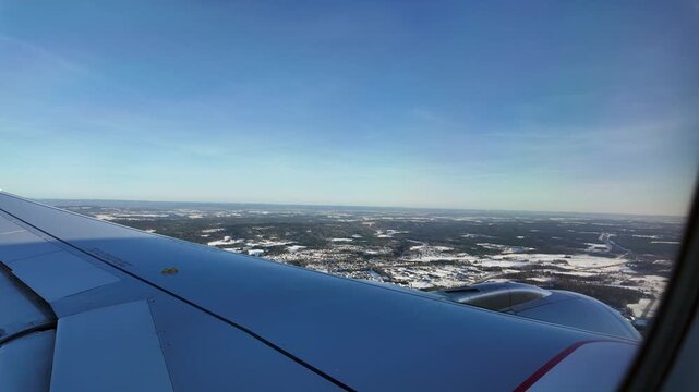A view out the window of a Scandinavian Airlines aircraft flying low over a winter landscape on approach to Oslo Airport Gardermoen.