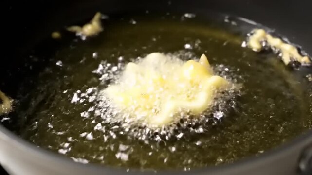 Golden crispy batter sizzling and bubbling in hot deep frying oil, capturing the delicious culinary process and tempting aroma of freshly cooked food