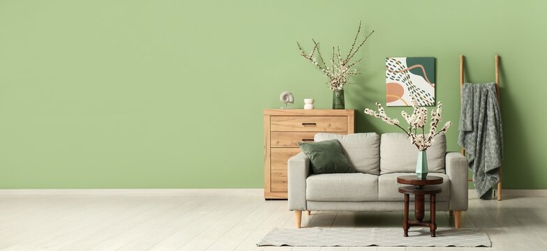 Interior of room with sofa and blooming branches. Banner for design