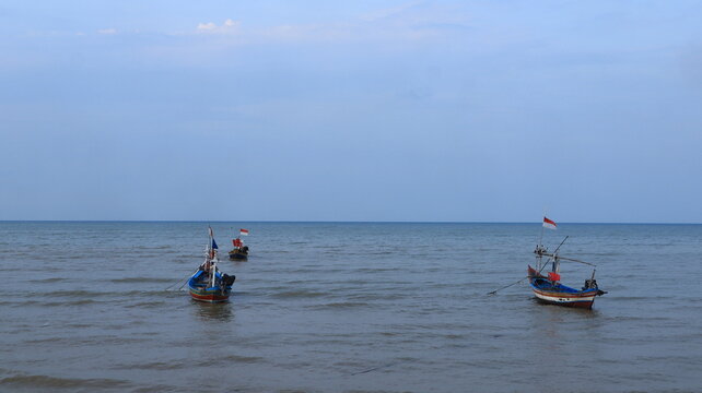 Two fishing boats made of wood anchored on the north coast of Tuban, East Java, Indonesia at dusk.