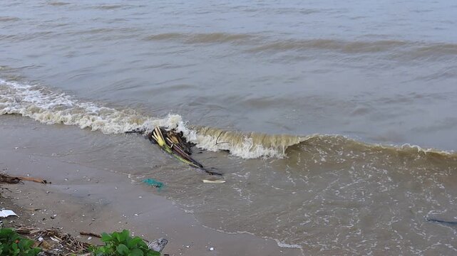 Ocean waves crash against the brown sandy beach in the north coast tourist area of ​​Tuban, East Java, Indonesia.