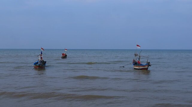 Fishing boats made of wood with red and white flags are moored on the north coast of Tuban, East Java, Indonesia.