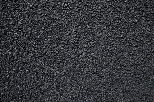 Close up view of dark grey asphalt road surface texture with small crushed stone aggregate