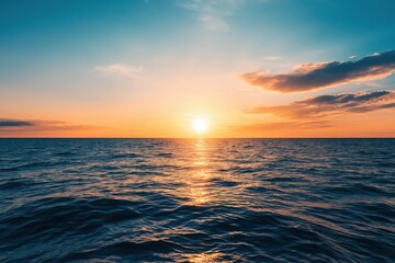 Fototapeta premium Sun sinking beneath the horizon, bathing calm sea and sky in warm orange and blue hues with soft reflections on the water