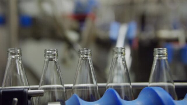 Glass Bottles on Production Line: A close-up view of empty glass bottles moving along a conveyor belt, showcasing the automated process of modern manufacturing