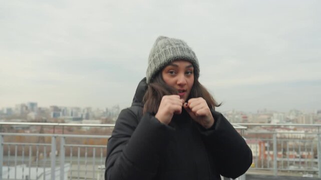 Rooftop dance rehearsal woman moving rhythmically across skyline, playful shadowboxing beats, knit beanie and winter coat, candid portrait frames, performer improvisation, confidence building