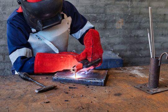 Professional Welder Performing Manual Metal Arc Welding on Steel Plate in a workshop.