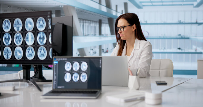 Female Neurologist Analyzing Brain MRI On Computer Screen