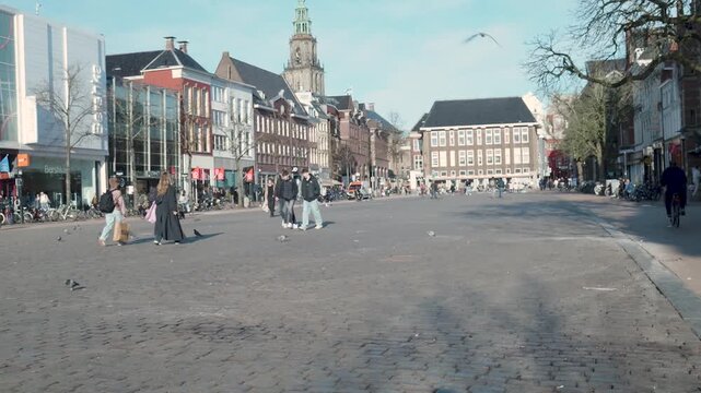 People walking in groningen's grote markt square with the martinitoren
