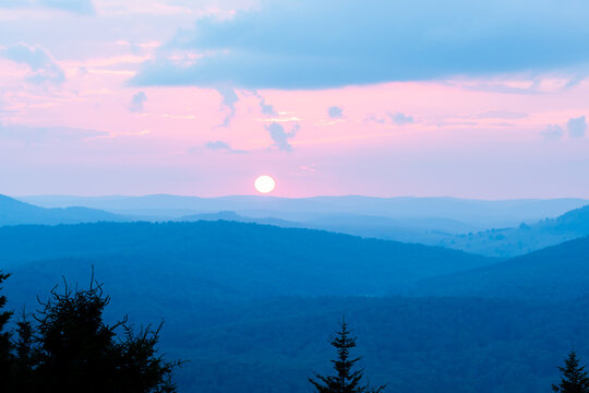 sun setting over rows and rows of blue ridge mountains in the distance and threatening to else over the horizon soon