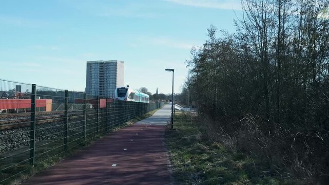High-speed passenger train passing a modern cycling path