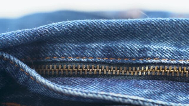 Close up of denim zipper detail with metal teeth and stitching.