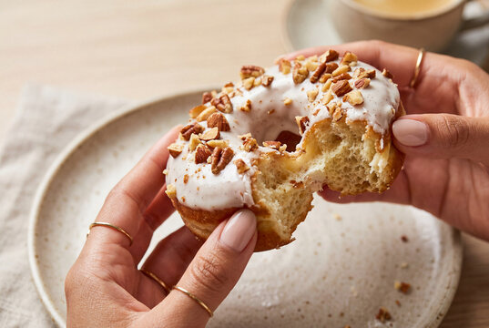 Female hands holding a half eaten gourmet glazed nut donut