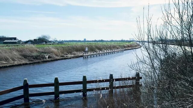 Dutch polder landscape with a river flowing under a blue sky
