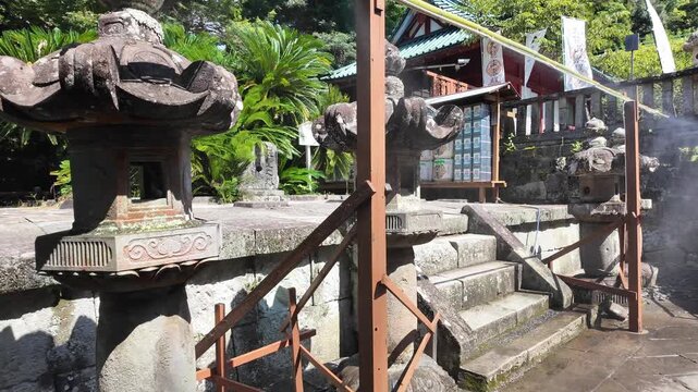 夏の神社に設置されたミストシャワー 猛暑の熱中症対策と涼を呼ぶ境内の風景 歴史ある石灯籠と緑 動画素材 4K
